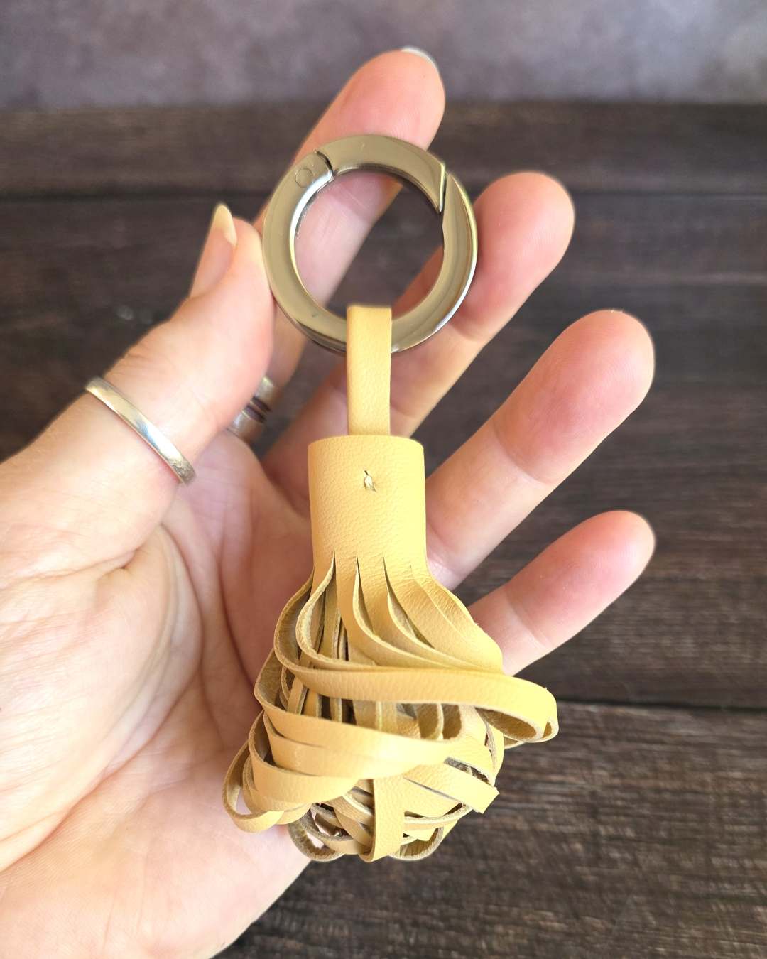 Pompon-porte-cle-en-cuir-camel-clair Porte clés en cuir camel clair torsadé avec un anneau mousqueton ouvert