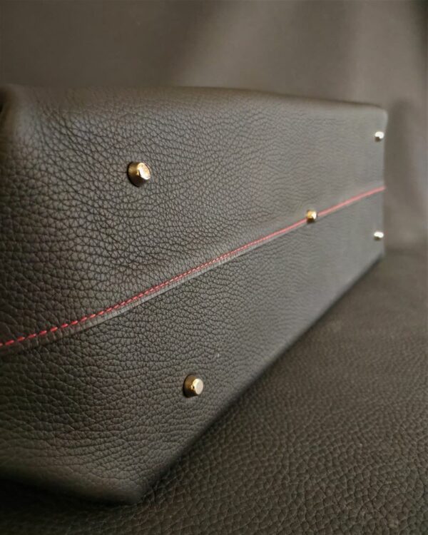 Un sac à main grand format en cuir grainé noir souple avec un fond en cuir rigide