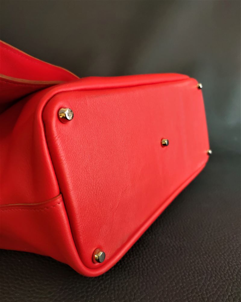 Sac à main besace asymétrique femme en cuir rouge fond avec cinq pieds de sac