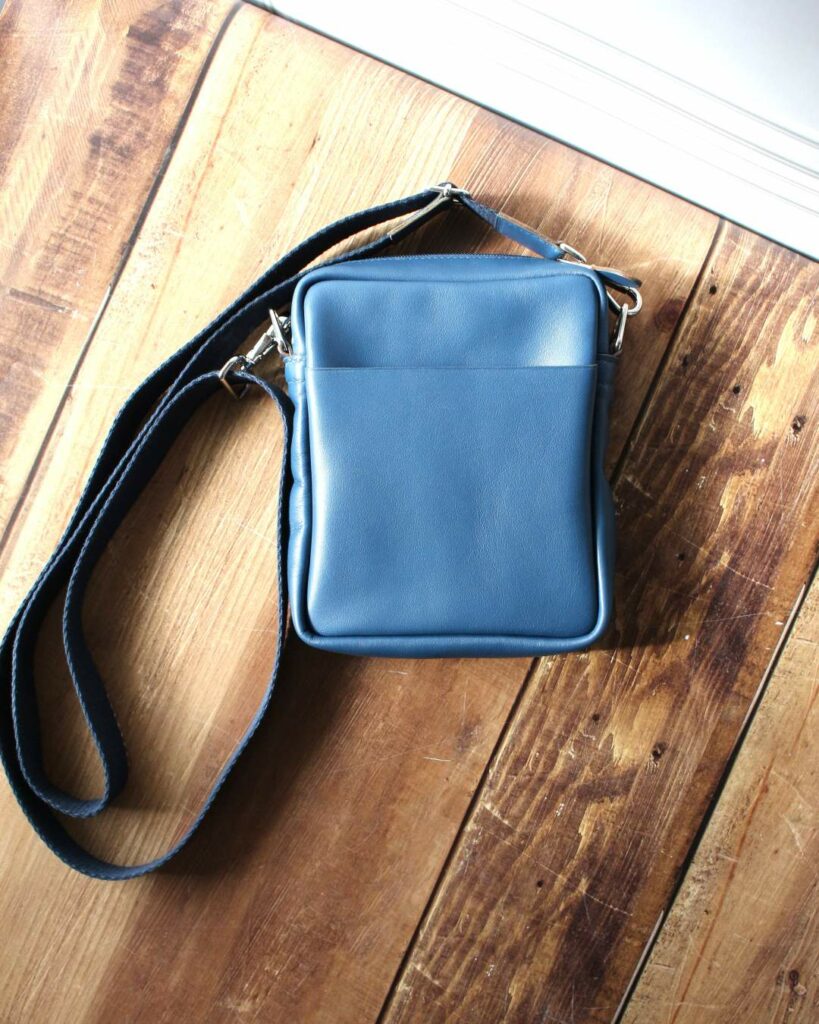 Sacoche pour homme en cuir bleu de forme rectangulaire avec une bandoulière en coton