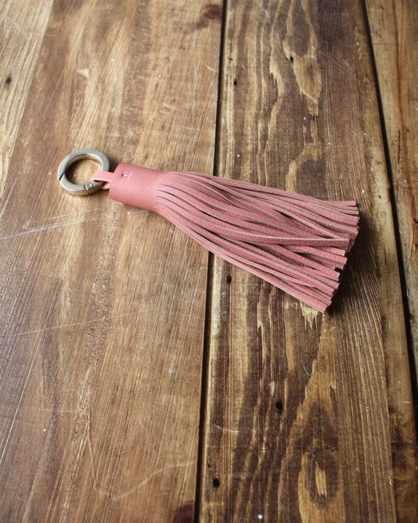 Porte clés pompon en cuir vieux rose à franges et avec un anneau ouvert mousqueton