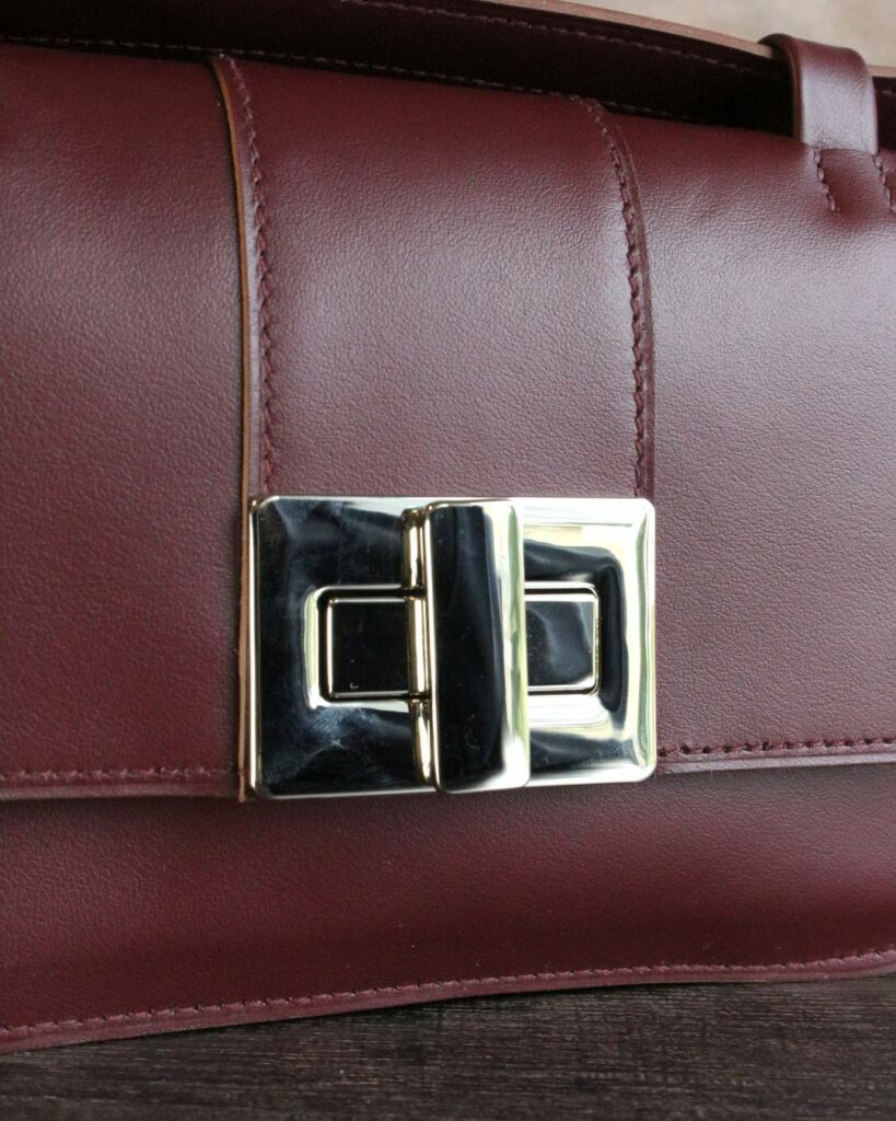 Petit sac bandoulière en cuir prune avec un très gros fermoir tourniquet nickelé