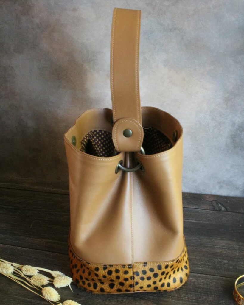 Sac seau en cuir imitation léopard sur le bas du sac et en cuir camel sur le haut du sac avec une anse amovible et bijouterie laiton viellit